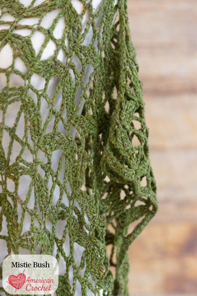 Flying Butterflies Poncho crochet pattern — olive green open lace poncho with wing-like drape on dress form, American Crochet bestseller