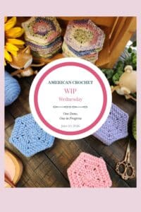 A tall Pinterest image featuring crocheted hexagons in soft blue, lavender, and pink solid colors alongside a stack of variegated spring pastel hexagons on a dark wood surface. A wooden fox figurine, a wooden bear figurine, yellow sunflowers, greenery, ornate scissors, a crochet hook, a skein of blue yarn, and a wood slice dish are styled around the hexagons. A white circle badge in the center reads "American Crochet — WIP Wednesday — One Done, One in Progress — June 10, 2026." A soft pink border frames the image.