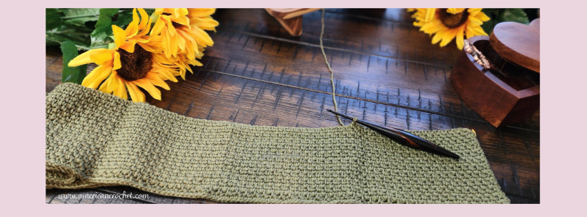 Golden Linen Wrap crochet in progress — olive cotton linen stitch on a wooden hook, styled with sunflowers on dark wood, American Crochet