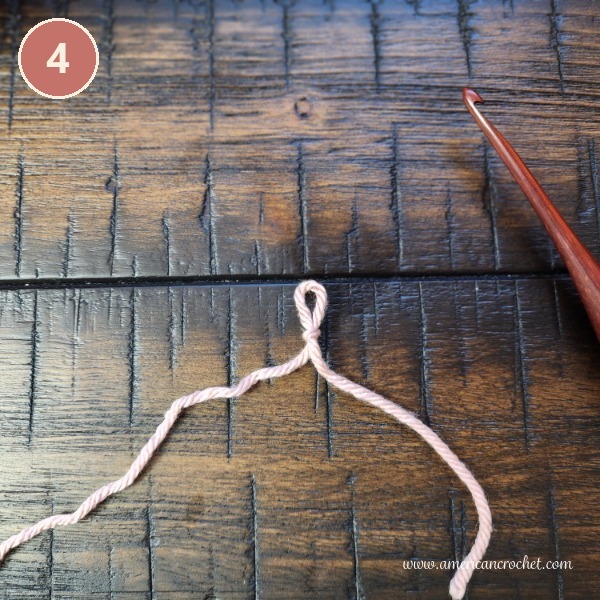 Step 4 - the finished crochet slip knot beside a wooden crochet hook.