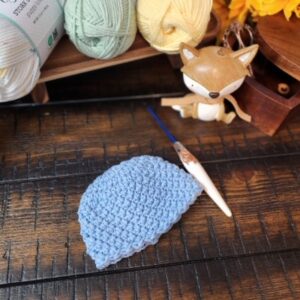 Sophie's Little Blessing Preemie Hat - a soft blue crochet preemie hat by American Crochet, styled with pastel yarn, sunflowers, and a little fox.