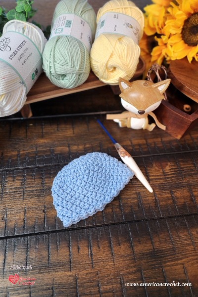 Sophie's Little Blessing Preemie Hat - a soft blue crochet preemie hat by American Crochet, styled with pastel yarn, sunflowers, and a little fox.