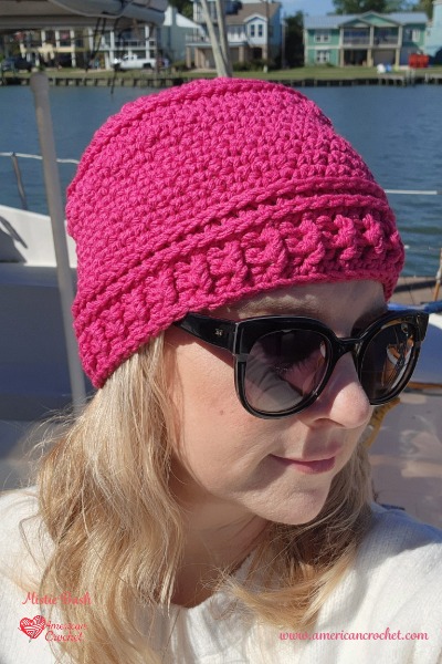 The Reba Beanie crochet hat pattern, a pink beanie with a ribbed brim, by American Crochet